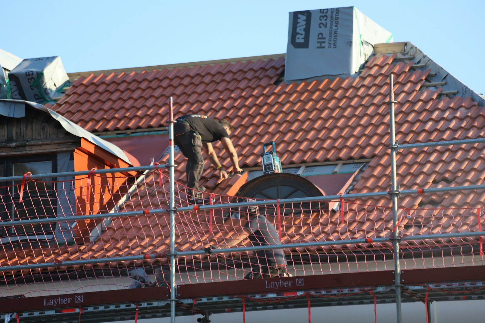 Roofer fastening shingles on a residential roof